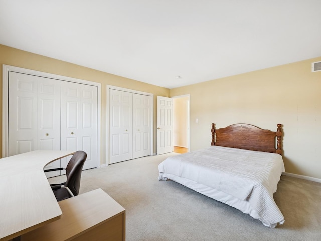 bedroom featuring multiple closets and light carpet