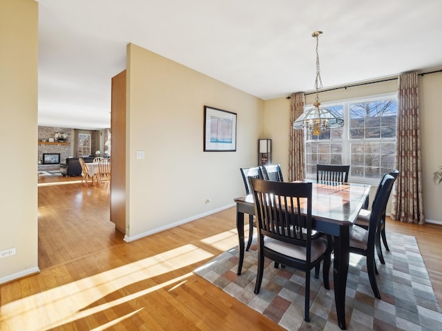 dining area featuring an inviting chandelier, wood-type flooring, and a large fireplace