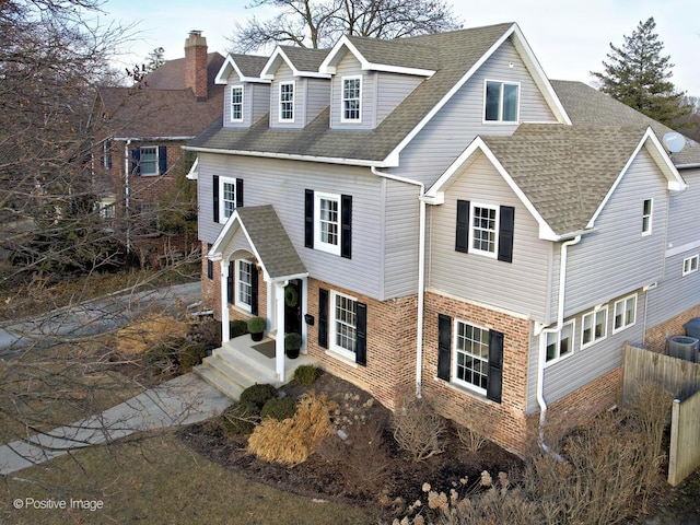 view of front of home featuring a shingled roof, a chimney, and brick siding