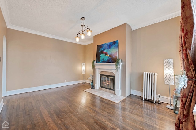 unfurnished living room featuring crown molding, a textured ceiling, dark hardwood / wood-style flooring, radiator, and a tile fireplace