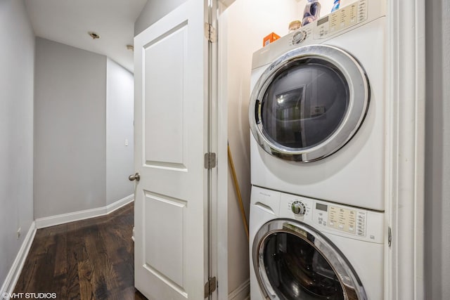 laundry area with stacked washer and dryer and dark hardwood / wood-style flooring