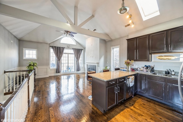 kitchen with a fireplace, dark wood-type flooring, ceiling fan, light stone counters, and dark brown cabinets