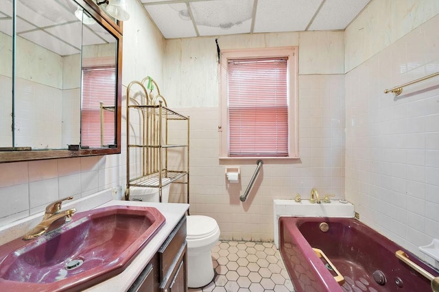 bathroom with tile walls, vanity, tile patterned floors, a tub, and toilet