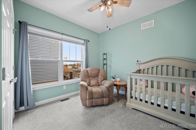 bedroom with a crib, carpet floors, and ceiling fan