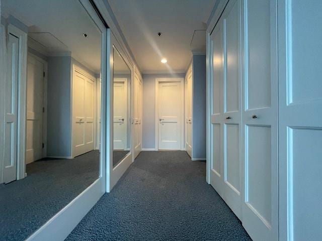 hallway with dark colored carpet and crown molding