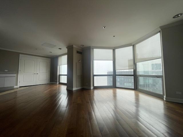 empty room with expansive windows, wood-type flooring, and crown molding