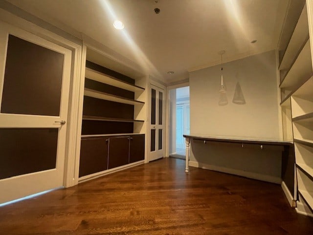 interior space with built in shelves and dark hardwood / wood-style flooring