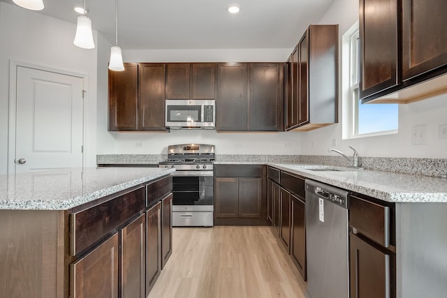 kitchen featuring decorative light fixtures, sink, dark brown cabinetry, stainless steel appliances, and light hardwood / wood-style flooring