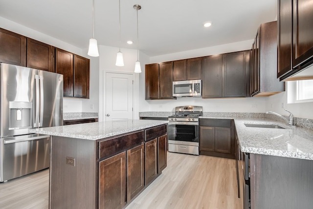 kitchen featuring dark brown cabinetry, sink, decorative light fixtures, a center island, and stainless steel appliances