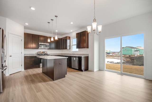 kitchen with hanging light fixtures, dark brown cabinets, a center island, and appliances with stainless steel finishes