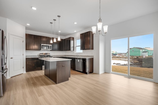 kitchen with dark brown cabinetry, appliances with stainless steel finishes, decorative light fixtures, and a center island