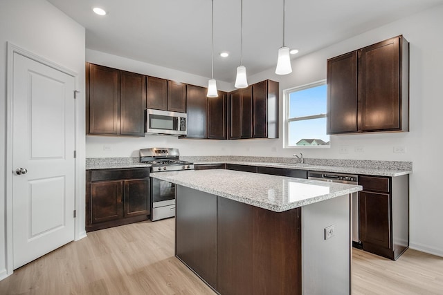 kitchen with a center island, dark brown cabinets, hanging light fixtures, light hardwood / wood-style flooring, and appliances with stainless steel finishes