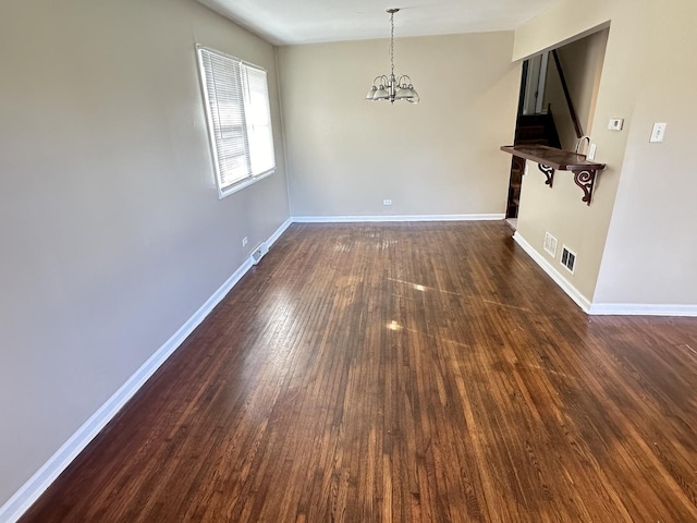 unfurnished room featuring dark hardwood / wood-style floors and an inviting chandelier