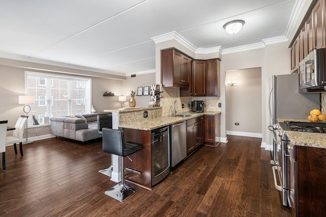 kitchen with appliances with stainless steel finishes, a kitchen breakfast bar, light stone counters, and crown molding