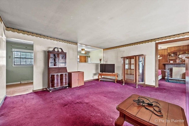 unfurnished living room with carpet floors, a brick fireplace, baseboards, and a ceiling fan