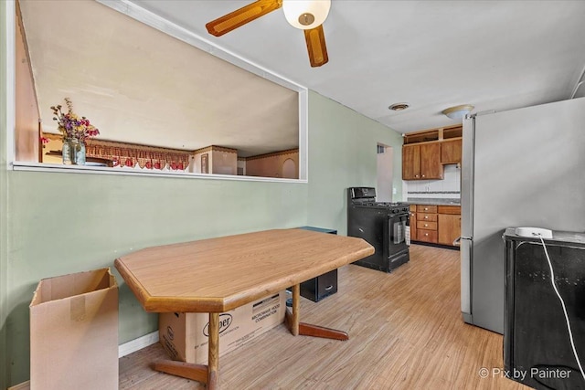 dining space featuring ceiling fan, light wood-style flooring, and baseboards