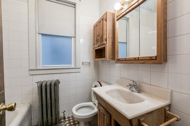 bathroom featuring vanity, toilet, radiator, and tile walls