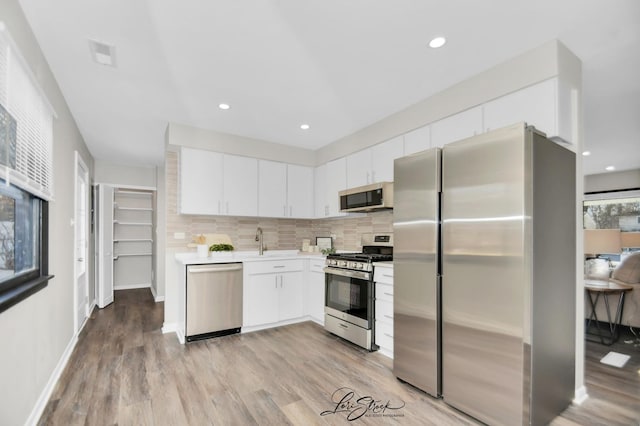 kitchen with tasteful backsplash, appliances with stainless steel finishes, and white cabinets