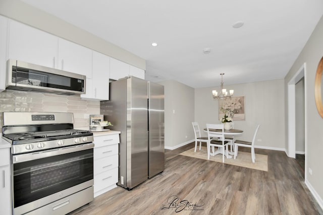 kitchen featuring white cabinetry, decorative light fixtures, decorative backsplash, and appliances with stainless steel finishes