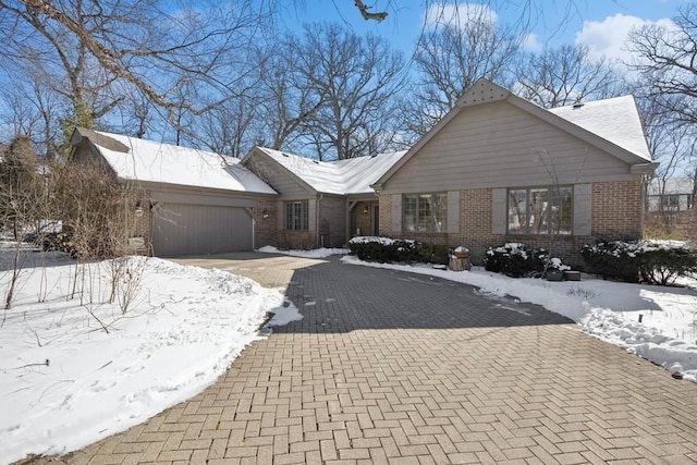 ranch-style house featuring brick siding, decorative driveway, and an attached garage