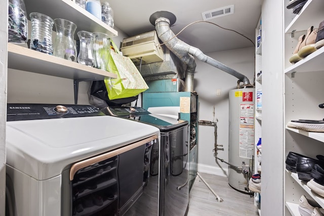 washroom with gas water heater and washing machine and clothes dryer