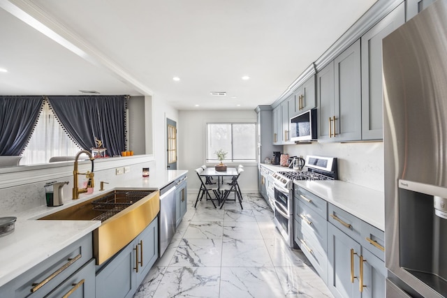 kitchen with sink, gray cabinets, stainless steel appliances, and light stone countertops