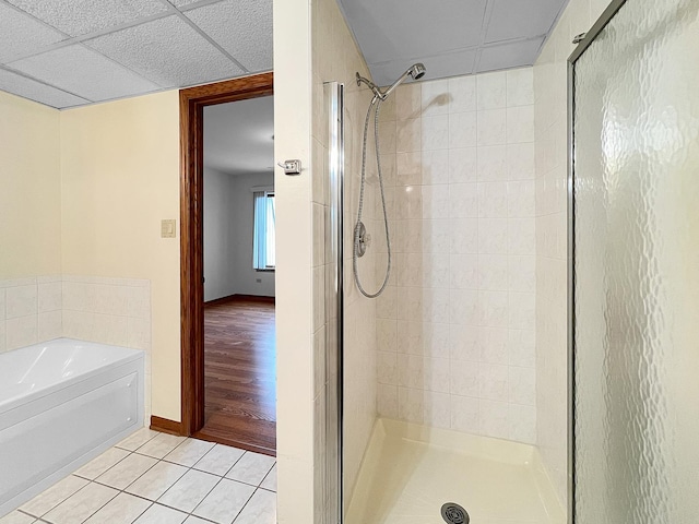 bathroom with a paneled ceiling, tile patterned floors, and shower with separate bathtub