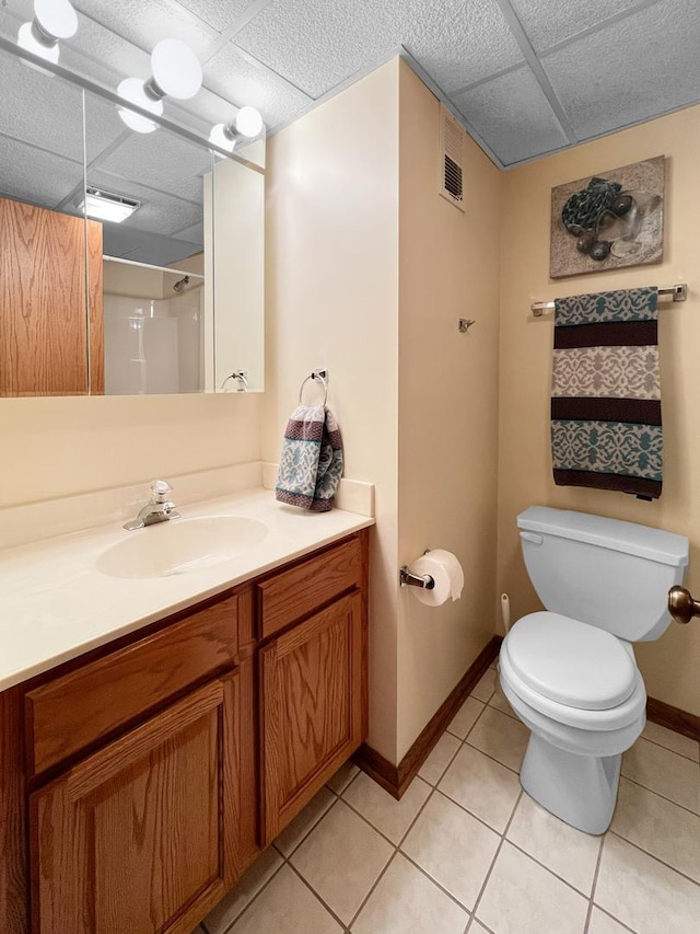 bathroom featuring tile patterned flooring, vanity, a paneled ceiling, and toilet