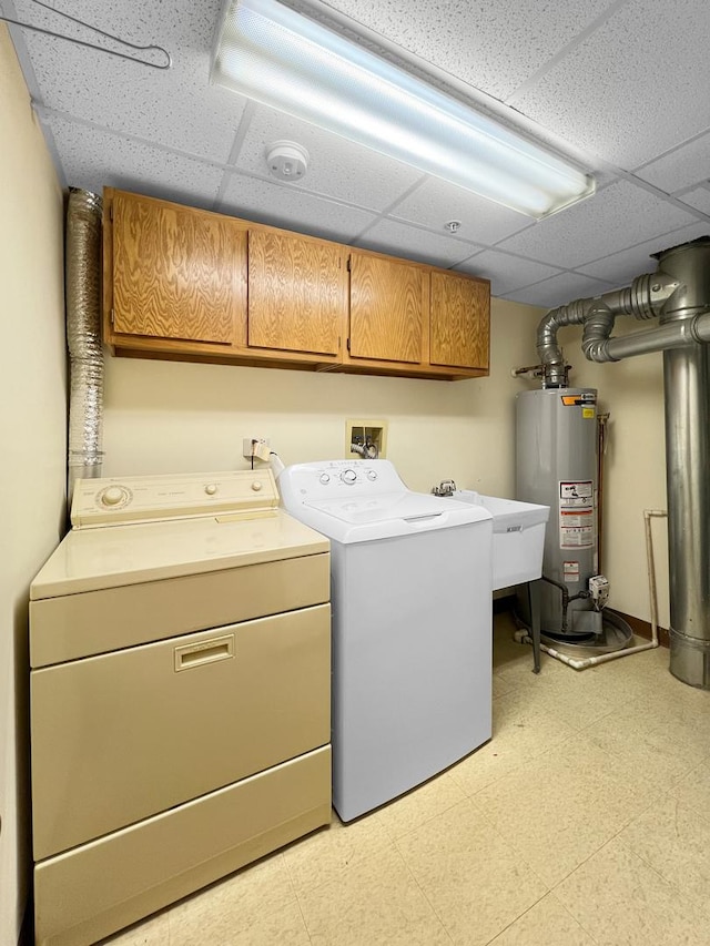 clothes washing area with water heater, sink, washing machine and clothes dryer, and cabinets