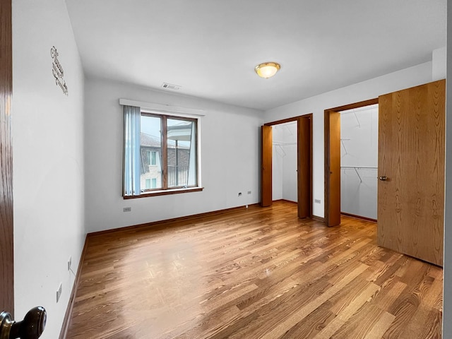 unfurnished bedroom with multiple closets and light hardwood / wood-style floors