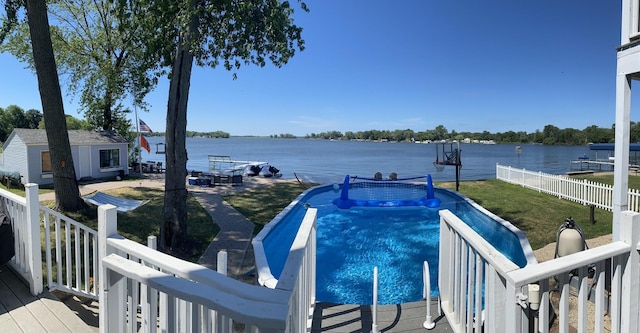 view of pool with a deck with water view, an outbuilding, and a lawn