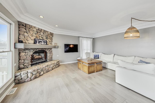 living room featuring crown molding, a stone fireplace, and light hardwood / wood-style floors