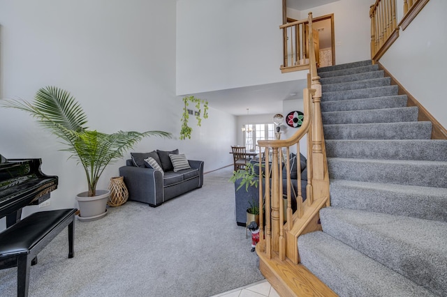 stairs with carpet floors, a towering ceiling, and a notable chandelier