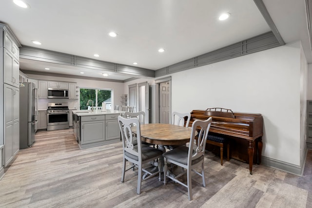 dining area featuring ornamental molding, sink, and light hardwood / wood-style floors