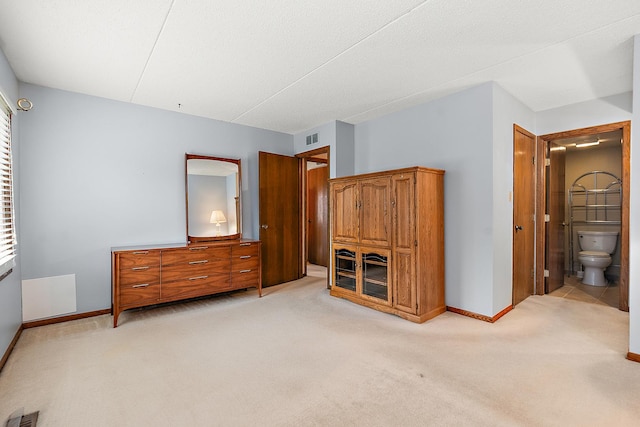 bedroom with connected bathroom and light carpet