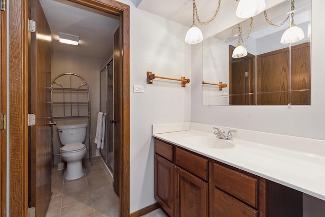 bathroom featuring tile patterned flooring, vanity, a shower with shower door, and toilet