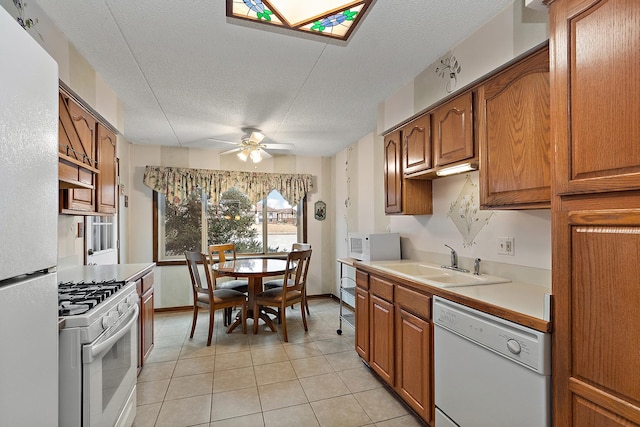 kitchen featuring sink, white appliances, a textured ceiling, light tile patterned floors, and ceiling fan