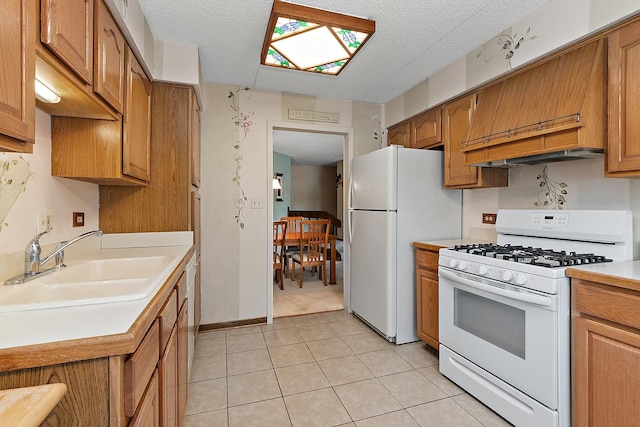 kitchen with sink, light tile patterned floors, a textured ceiling, and white appliances