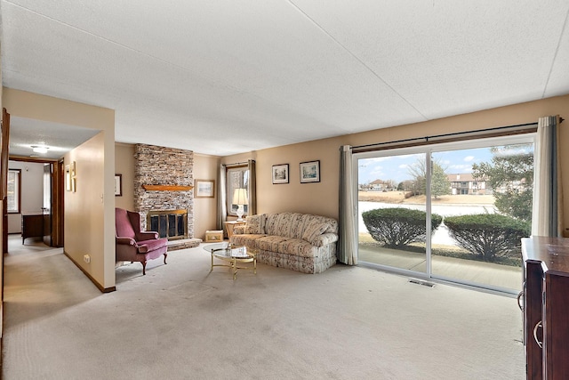 carpeted living room with a stone fireplace and a textured ceiling