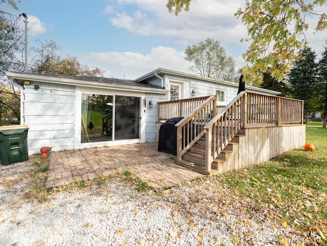 rear view of house with a wooden deck and a patio area