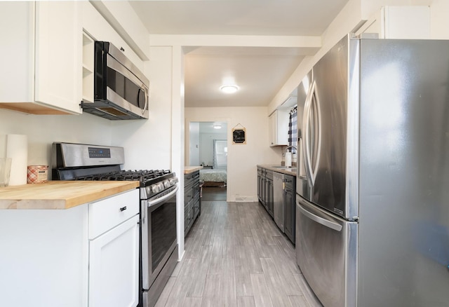 kitchen with sink, butcher block countertops, light hardwood / wood-style flooring, stainless steel appliances, and white cabinets