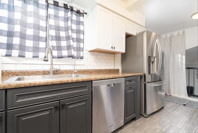 kitchen featuring tasteful backsplash, sink, white cabinets, and appliances with stainless steel finishes