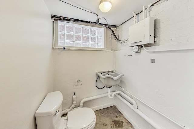 bathroom with concrete flooring, toilet, and electric panel