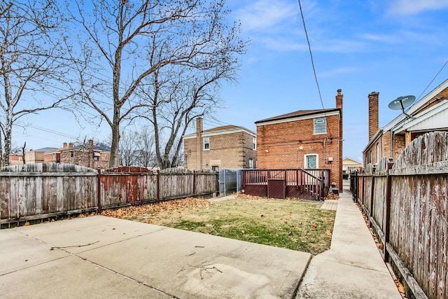 back of property featuring a wooden deck, a yard, and a patio area