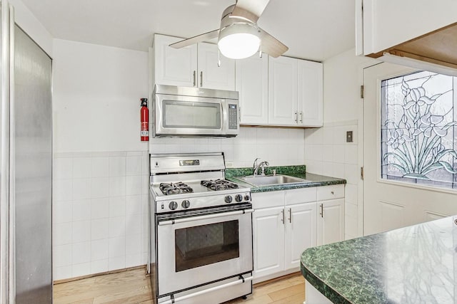 kitchen featuring stainless steel appliances, sink, light hardwood / wood-style flooring, and white cabinets