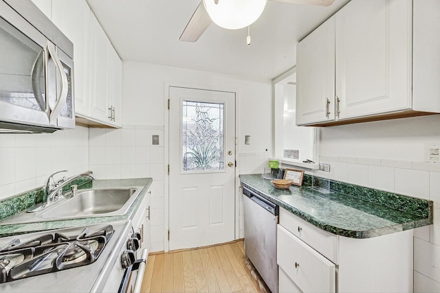 kitchen featuring sink, tile walls, stainless steel appliances, white cabinets, and light wood-type flooring