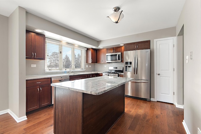 kitchen featuring sink, tasteful backsplash, a center island, appliances with stainless steel finishes, and dark hardwood / wood-style floors