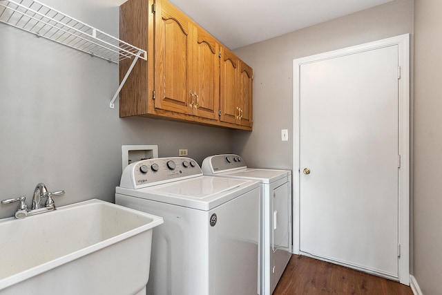 clothes washing area with cabinets, dark hardwood / wood-style flooring, sink, and washer and dryer