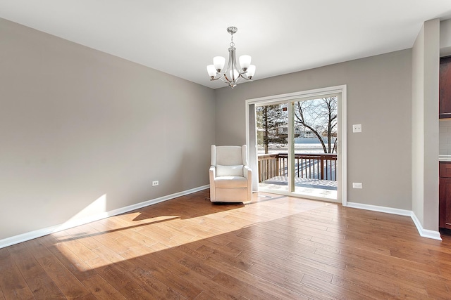 unfurnished room with an inviting chandelier and light hardwood / wood-style flooring