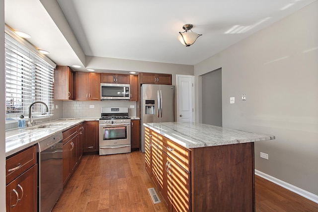 kitchen featuring light stone counters, appliances with stainless steel finishes, dark hardwood / wood-style flooring, and sink